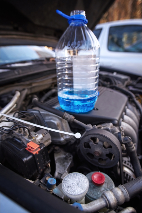 Pouring winter washer fluid into car reservoir during winter, protecting it  from freezing. Stock Photo by halfpoint