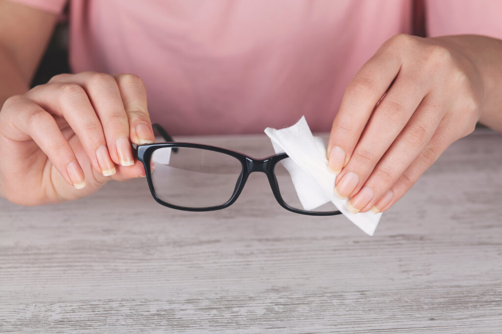 A woman cleaning a pair of eyeglasses. 